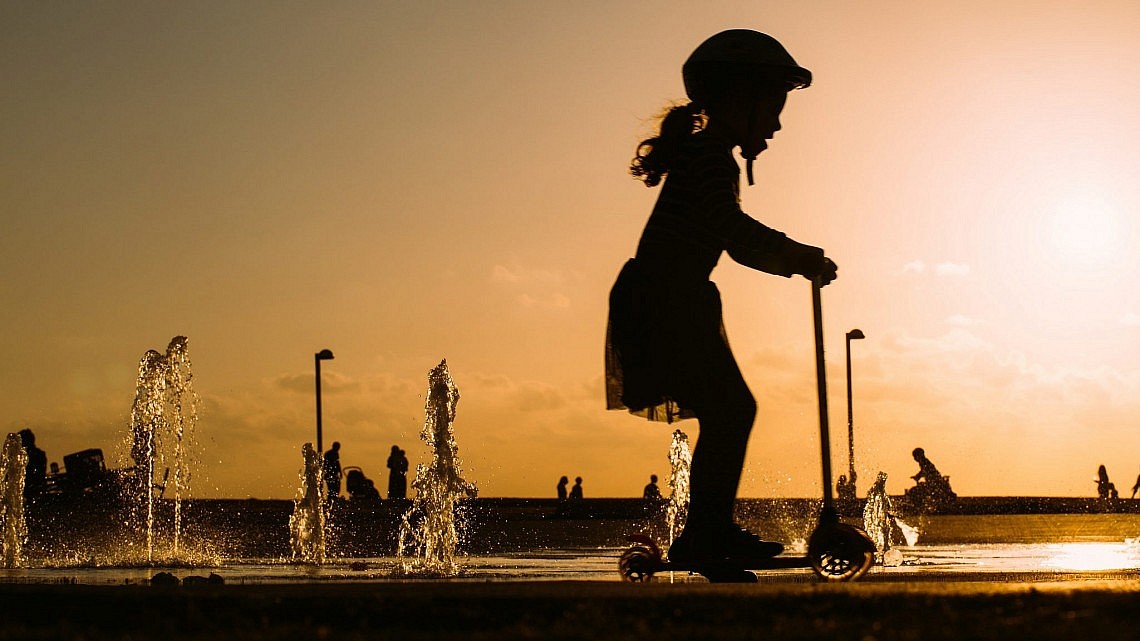 ילדה על קורקינט בתל אביב. הולך להיות הרבה יותר חם (צילום: Shutterstock)