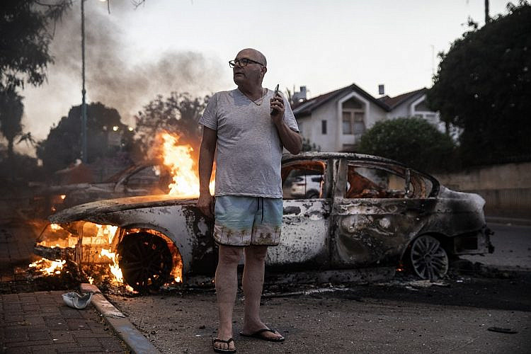 יעקב סימונה מחוץ לביתו ולצד מכוניתו השרופה בזמן המהומות בלוד (צילום: היידי לוין)