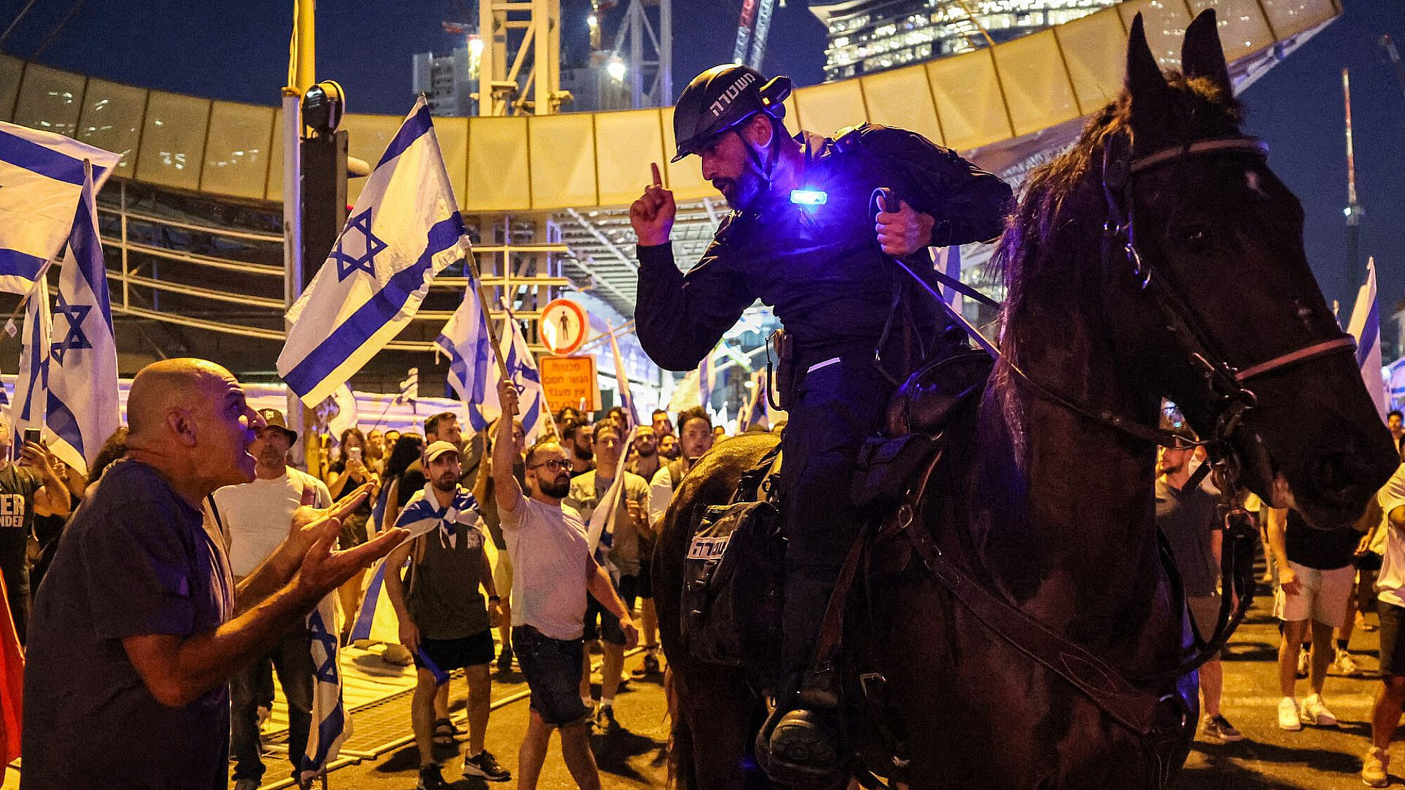 אלימות חד כיוונית זה לא "עימות". שוטר מאיים על מפגין ליד רכבת השלום, 24.7.23 (צילום: ג'ק גואז/AFP/גטי אימג'ס)